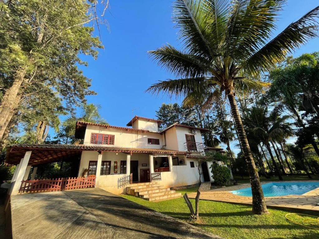 uma casa com uma palmeira e uma piscina em Casa do Lago - Mar de Minas - Lago de Furnas em Carmo do Rio Claro