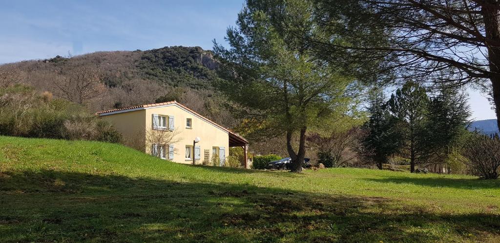 ein Haus auf einem grasbewachsenen Hügel mit einem Berg im Hintergrund in der Unterkunft Maisons situées dans le vaste domaine de l'espinet in Quillan
