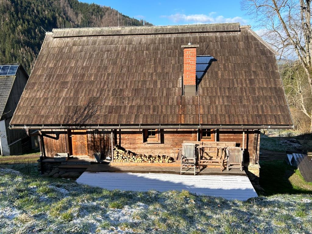 una casa con techo y un banco delante en Charmantes Gästehaus am Waldrand in alpiner Lage Siehe auch zweites Objekt Gästewohnung in altem Bauernhaus en Stanz Im Murztal