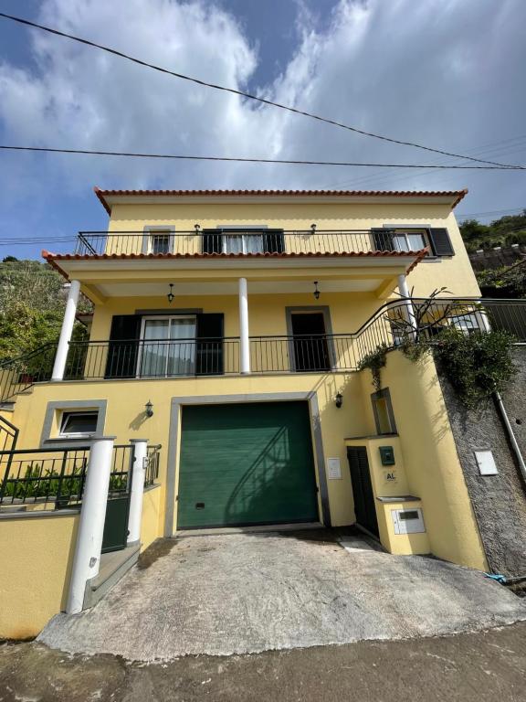 a yellow house with a green garage door at Dream Home in Calheta