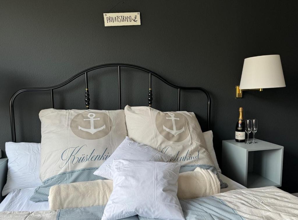 1 cama con almohadas blancas y un cartel en la pared en Pension Ostsee-Strand en Börgerende-Rethwisch