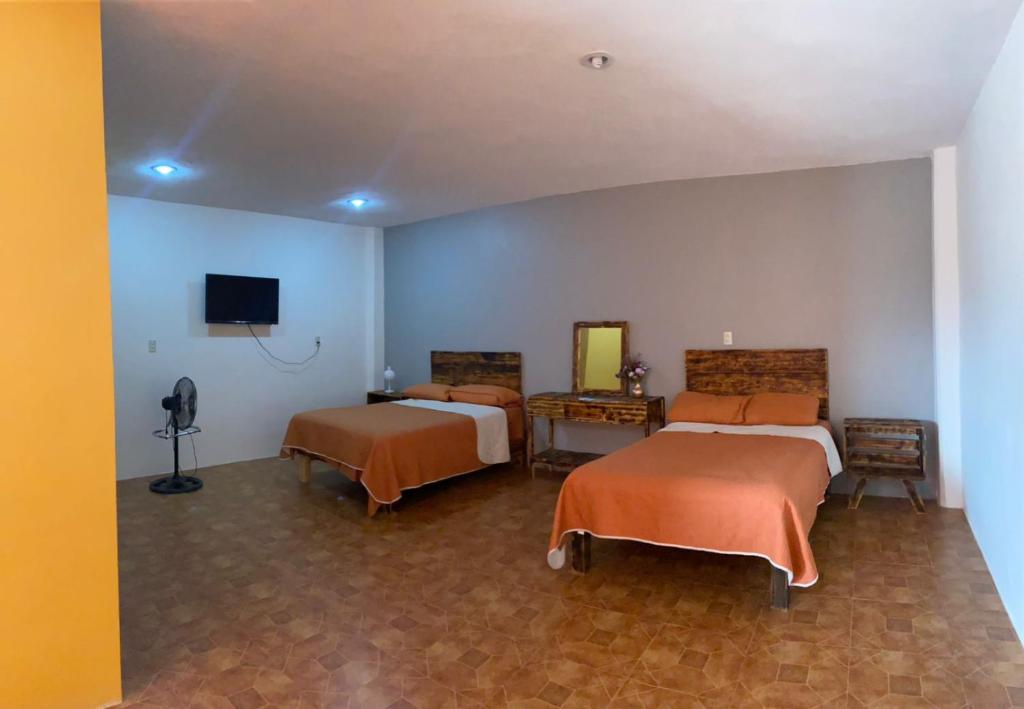 um quarto com duas camas e uma televisão na parede em Portal Malila em Tancama