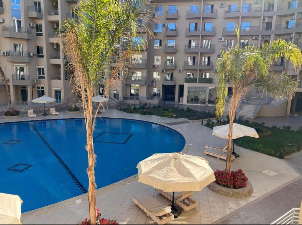 uma piscina com guarda-sóis e palmeiras em frente a um edifício em Princess Resort em Hurghada