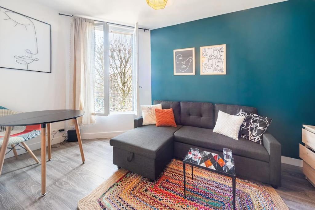 uma sala de estar com um sofá e uma mesa em Beau et Cosy studio - 8min Paris em Rosny-sous-Bois
