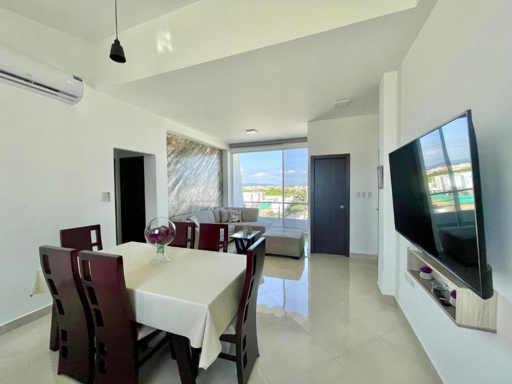 a dining room with a white table and a television at APARTAMENTO PUERTO MADERA in Manta