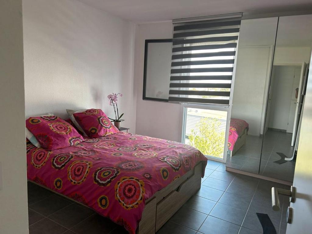 um quarto com uma cama com lençóis cor-de-rosa e uma janela em Cozy appartement em Aubervilliers