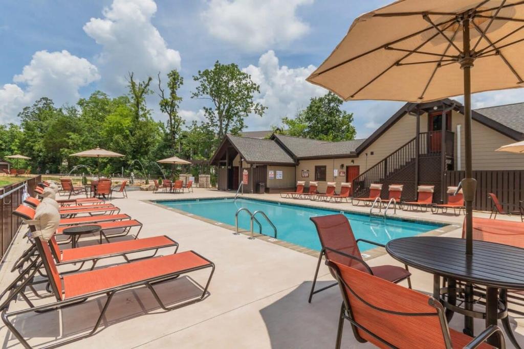a pool with chairs and tables and an umbrella at NEW 3 BR Apt ADA compliant Sleeps 8 in Pigeon Forge