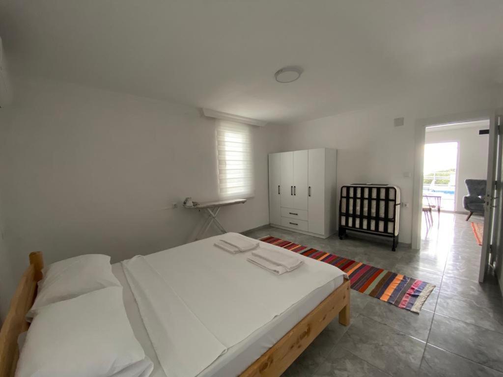 um quarto com uma grande cama branca e uma cadeira em Mavi Boncuk em Muğla