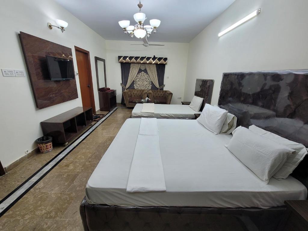a bedroom with two beds and a flat screen tv at Hotel Capital one in Karachi
