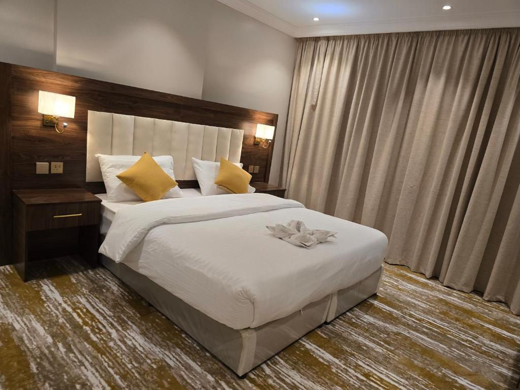 ein Schlafzimmer mit einem großen weißen Bett mit gelben Kissen in der Unterkunft سحابة الأحلام - Dream Cloud Hotel in Dschidda