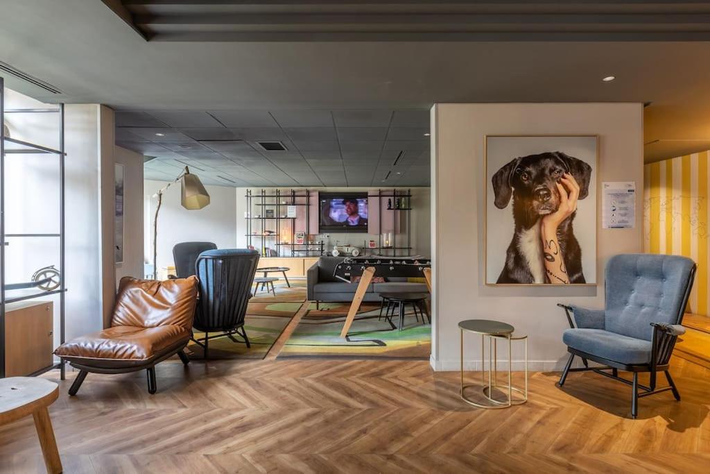un salon avec des chaises et une peinture d'un chien dans l'établissement Le CHARMANT Paris Expo Appart'hotel Adagio 4', à Issy-les-Moulineaux