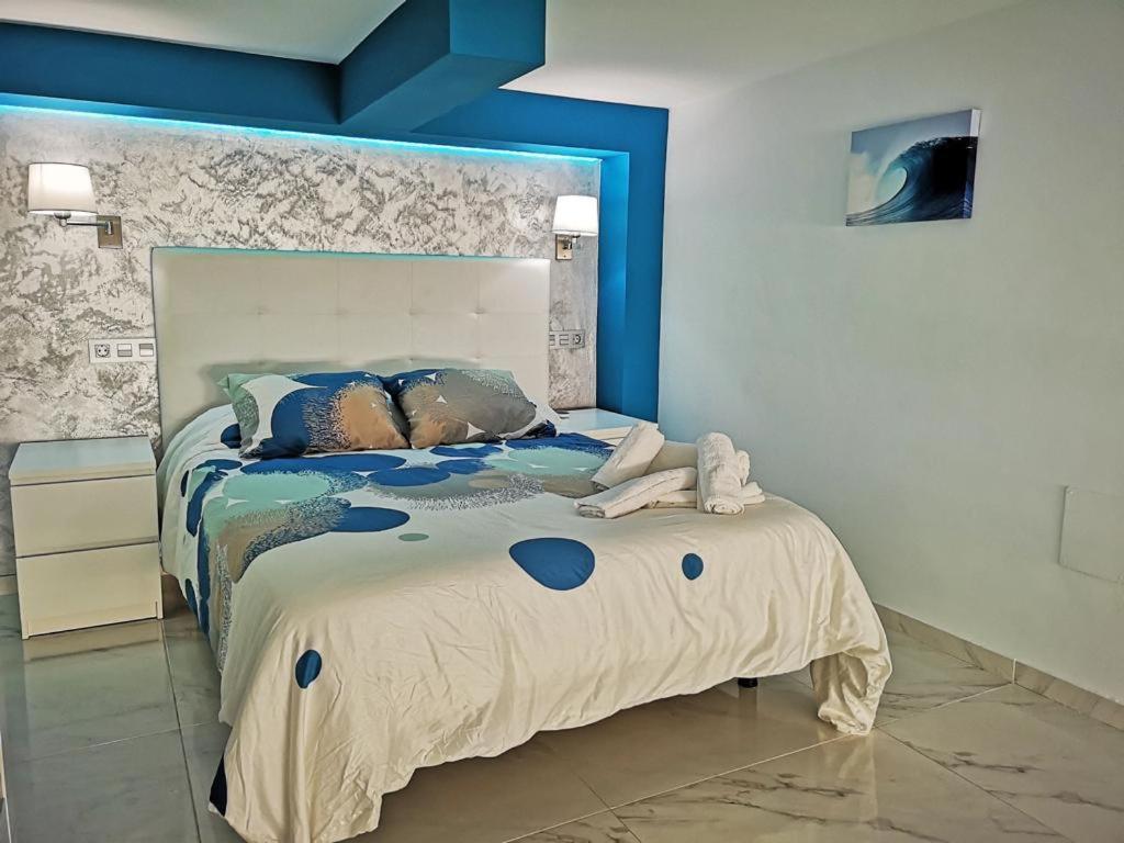 Un dormitorio con una cama grande con cabecero azul. en OFIC/ESTUDIO CONIL S.A., en Conil de la Frontera