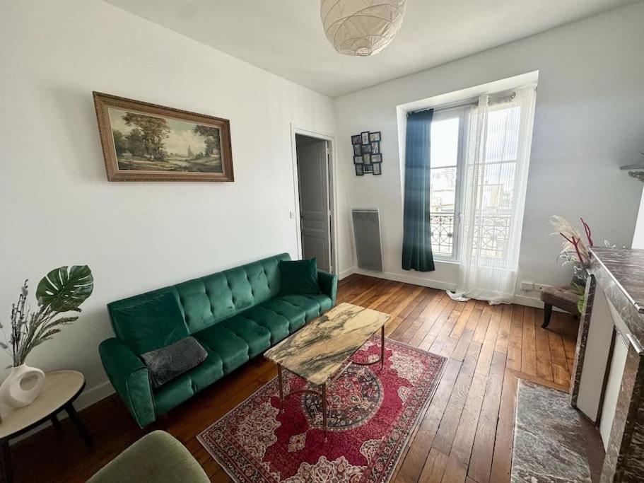 sala de estar con sofá verde y chimenea en Cosy appartement - La Villette, en París