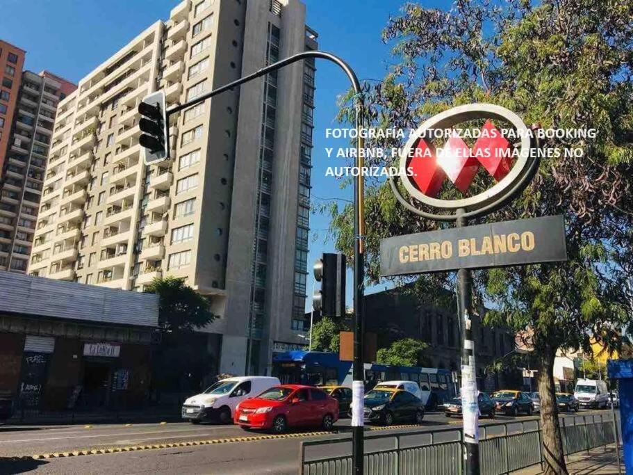 una señal de la calle frente a un edificio con un semáforo en Cómodo departamento Cerca de Metro en Santiago