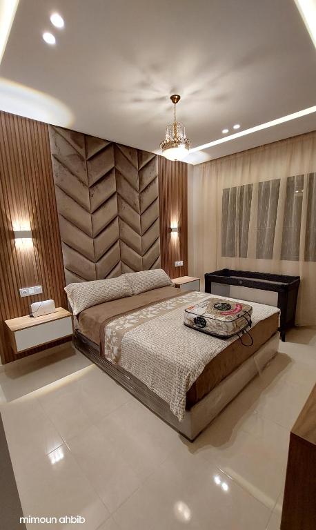 a bedroom with a large bed and a chandelier at اقامة الاحلام in Nador