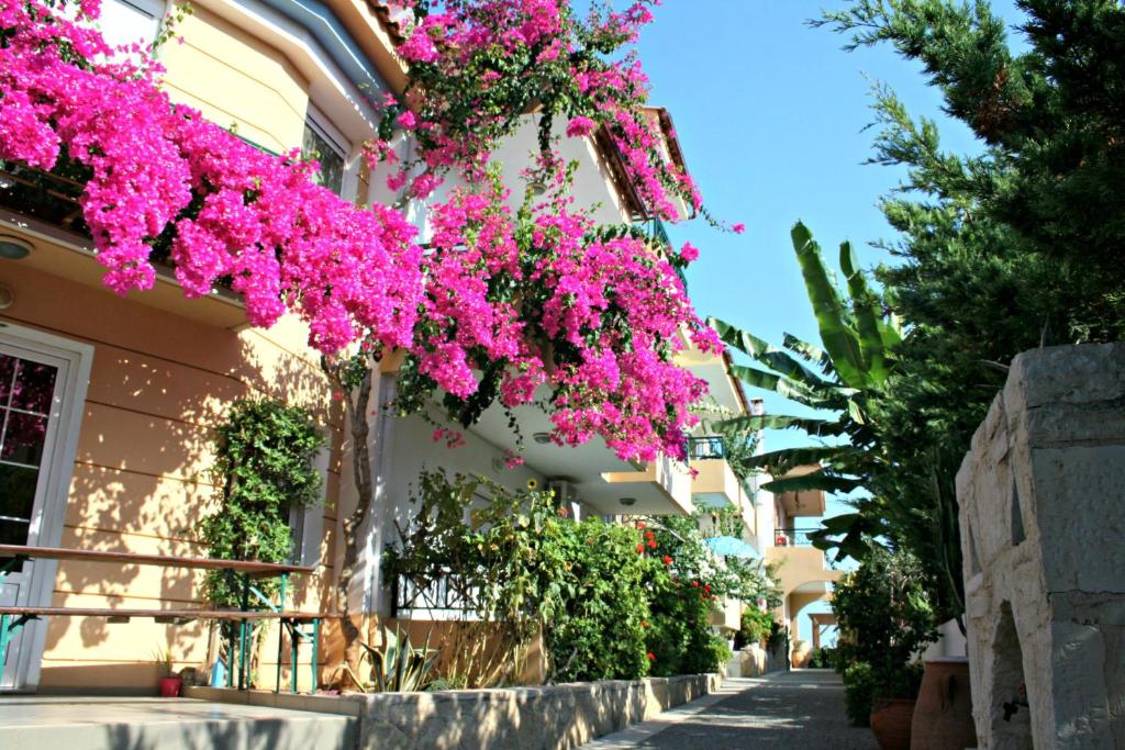 a building with pink flowers hanging from it at Minoica Beach Apartments in Amoudara Herakliou