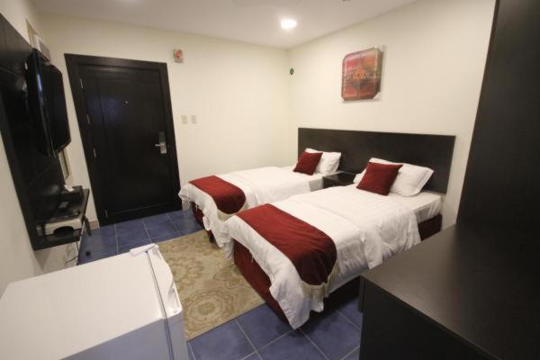 ein Hotelzimmer mit 2 Betten und einem TV in der Unterkunft شقق آن للشقق المخدومة in Al-Dschubail