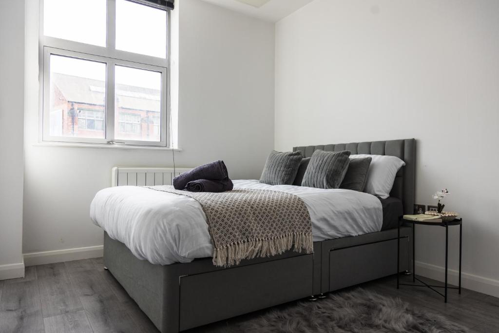 a bedroom with a bed with white sheets and a window at Modern and Comfy in City Centre PS4 , Free On Street Parking ,Walking Distance To Bus, Train Stations And Shopping Centres in Leicester