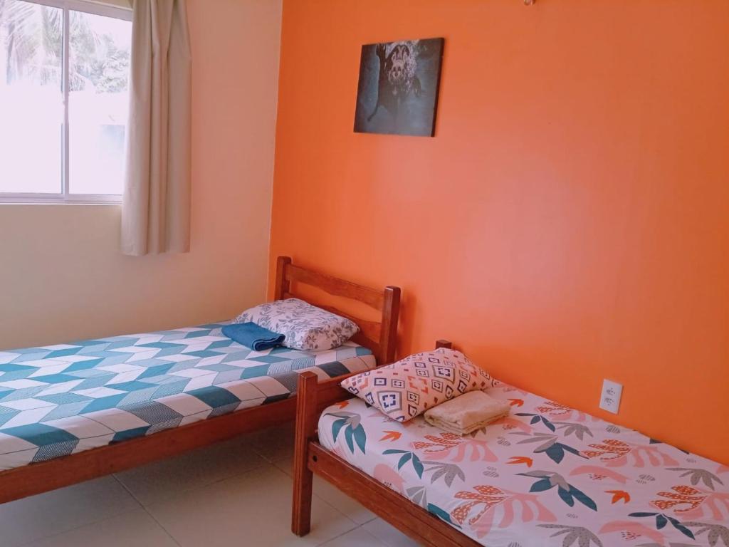 2 camas individuales en una habitación con paredes de color naranja en Pousada Vista Verde en Paracuru