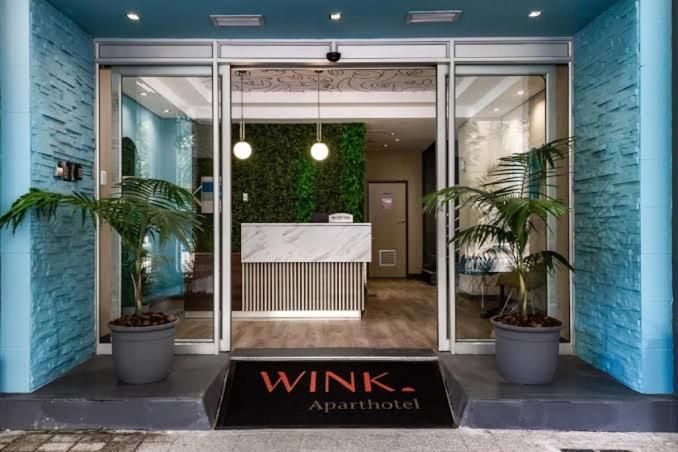 un ingresso in vetro a una cantina con due piante in vaso di WINK Hotel- Next to CTICC & Best Tourist Location a Città del Capo