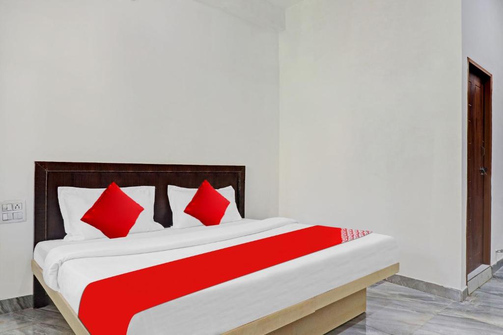 a red and white bed with red pillows on it at Collection O Cosmos Resort in Rājpur
