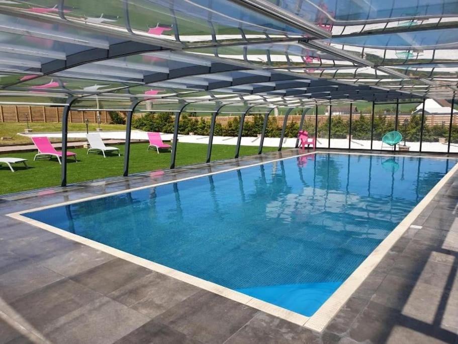 a large swimming pool in a building with pink chairs at La grange des rosiers in Cambron