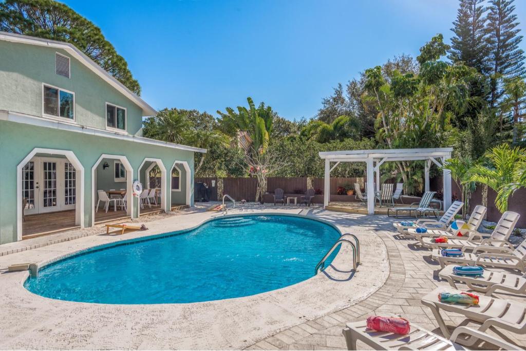 una piscina con tumbonas y una casa en Great 6BR for All Ages Heated Pool 5 Min to Beach, en Seminole