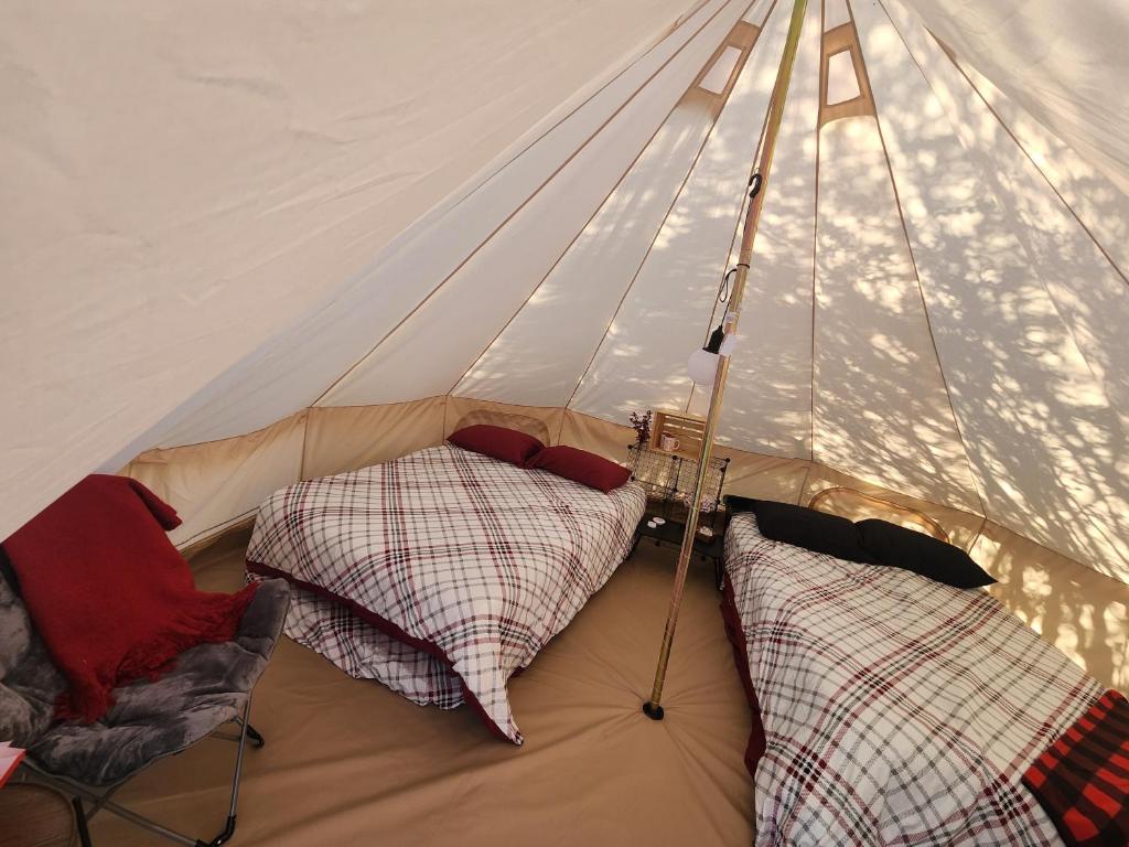 a tent with two beds and a chair in it at #5 Cabin Fever in Drumheller