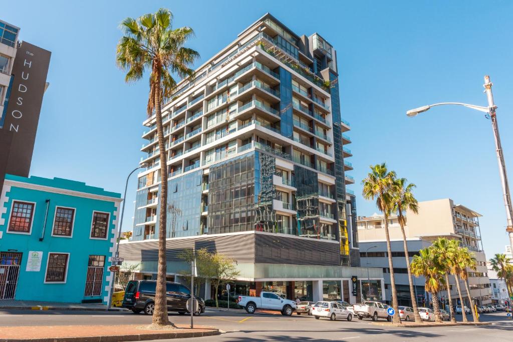 um edifício alto numa rua da cidade com palmeiras em Mirage by McStay em Cidade do Cabo
