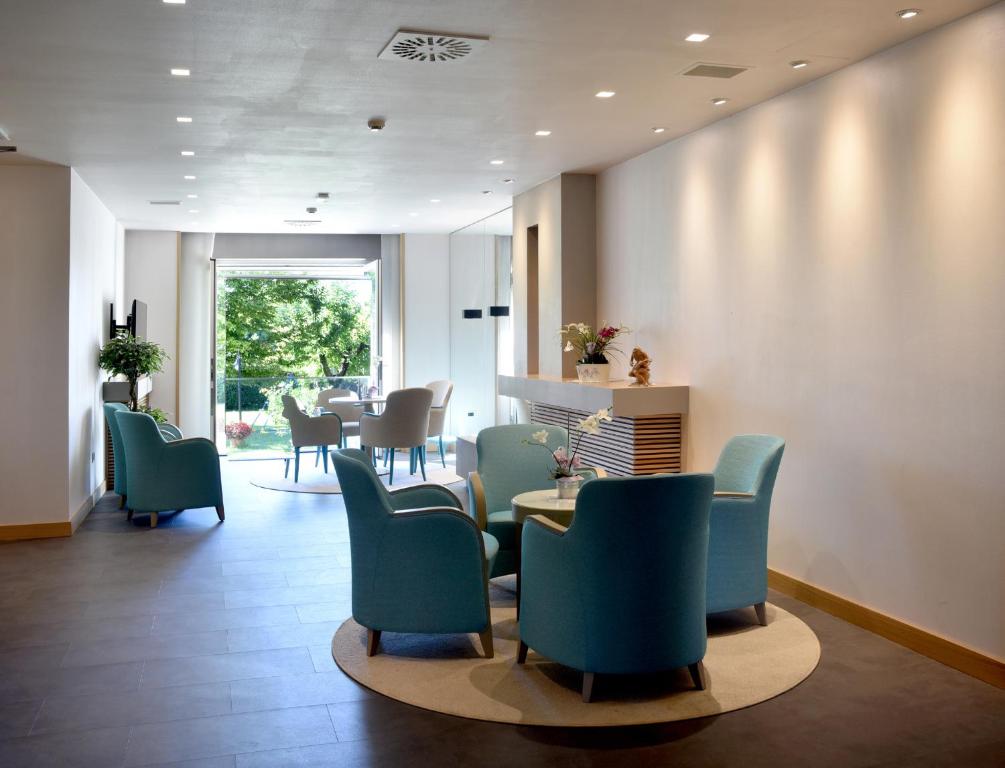 una sala de espera con sillas azules y una mesa en Hotel Italia, en Monfalcone