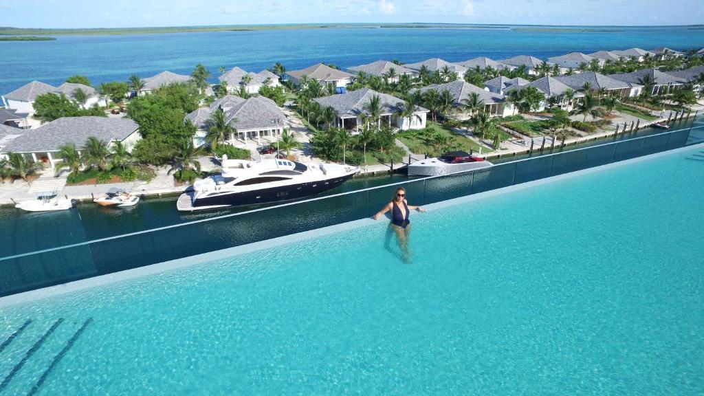 a man standing in the water in a pool with a resort at Hilton at Resorts World Bimini in Alice Town