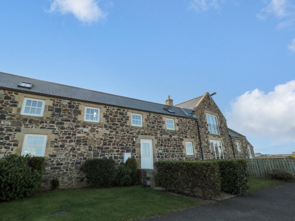 an old stone house with bushes in front of it at Low Croft in Alnwick