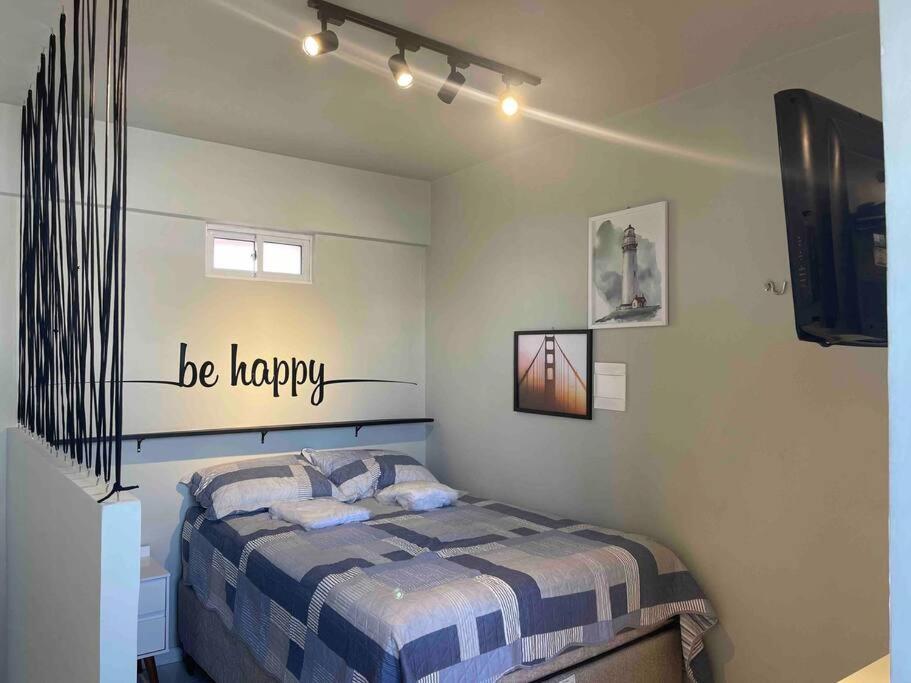 1 dormitorio con 1 cama y un cartel feliz en la pared en kitchenette espetacular na torre en João Pessoa