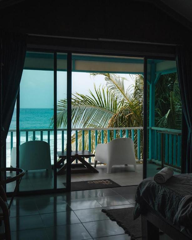 a bedroom with a view of the ocean from a balcony at Pondok Beach Shack in Tioman Island