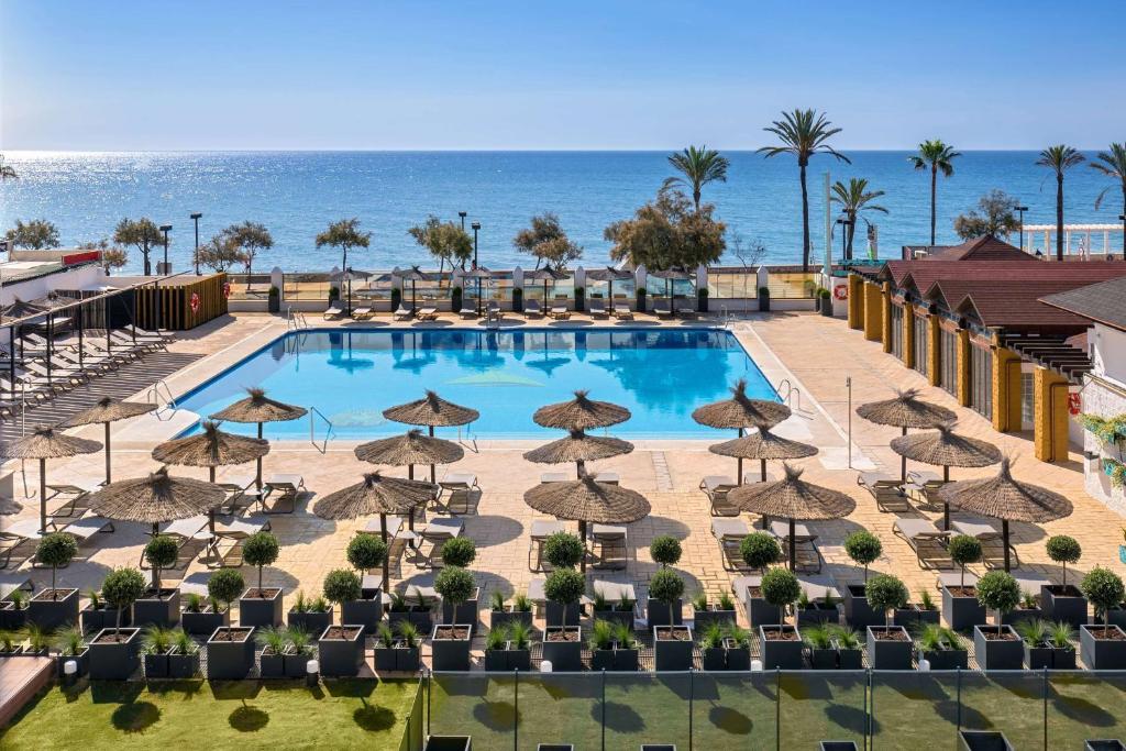 an overhead view of a swimming pool with chairs and umbrellas at Occidental Fuengirola in Fuengirola