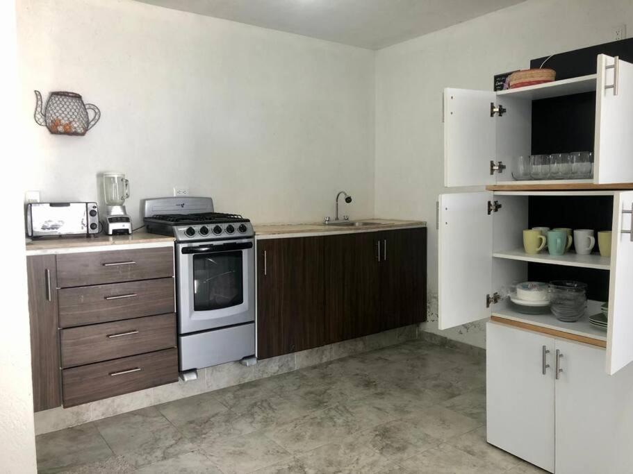 uma cozinha com um fogão e armários brancos em Casa amplia y Cómoda em Chapulco