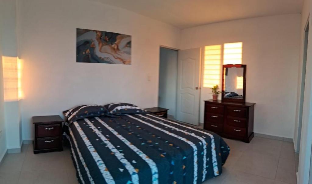 Schlafzimmer mit einem Bett, einer Kommode und einem Spiegel in der Unterkunft ALTOS DE VIRGINIA 57 in Sánchez