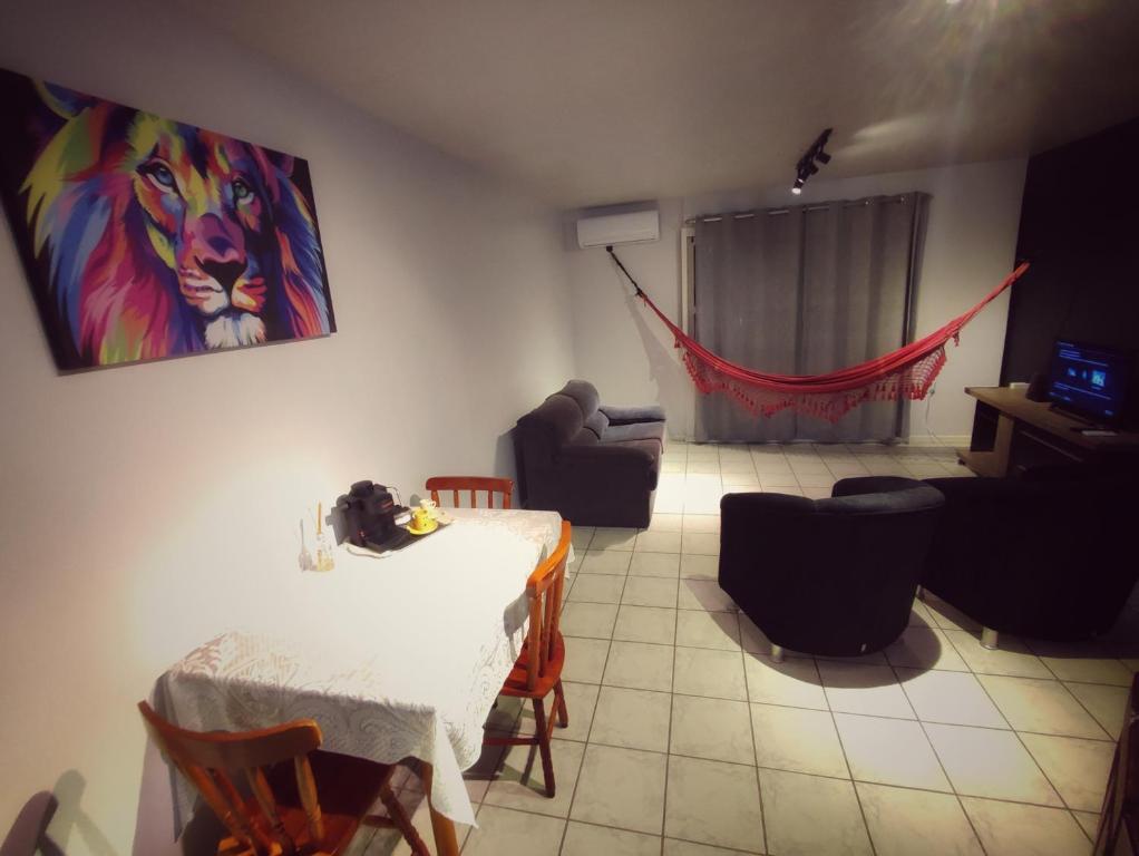 sala de estar con mesa, sillas y una pintura en Apartamento Parque Itaimbé - Centro - Garagem, en Santa Maria