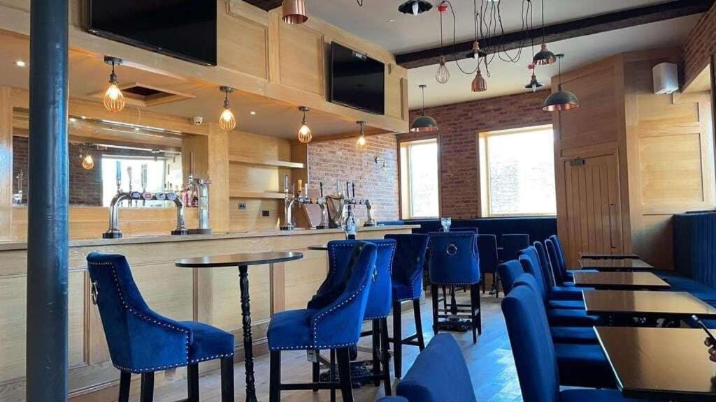 a bar with blue chairs and tables in a restaurant at The Royal Crest in Liverpool