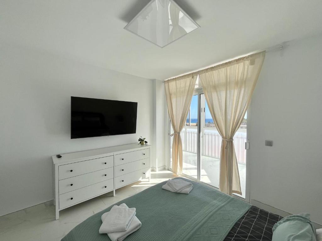 um quarto com uma televisão e uma cama com uma cómoda em Jandia Beach Apartment 2 em Morro del Jable