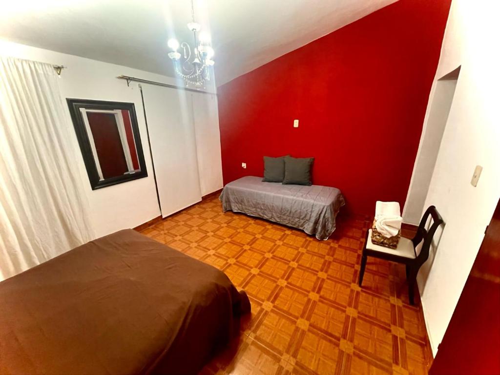 1 dormitorio con cama y pared roja en La Casa de Agos en La Rioja