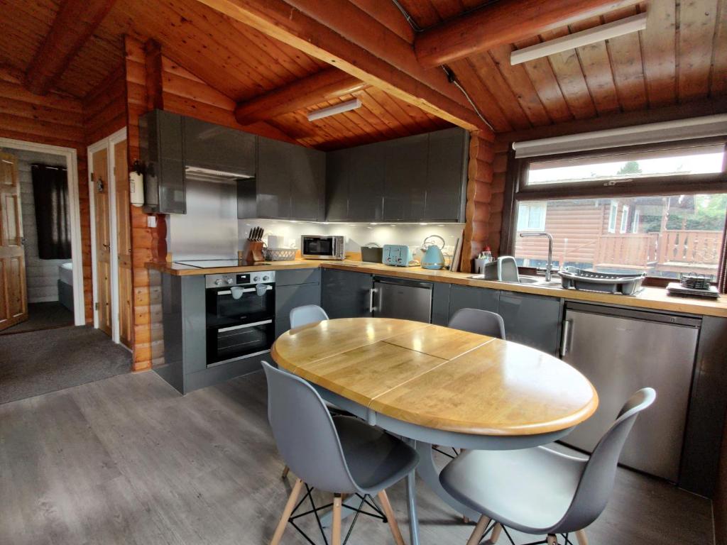 TrawsfynyddにあるSerene Snowdonia Retreatのキッチン(木製のテーブル、椅子付)