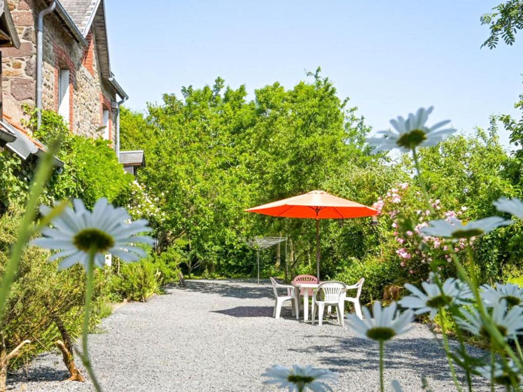 eine Terrasse mit einem Sonnenschirm, Stühlen und Blumen in der Unterkunft Gite Le Chevalier in Gavray