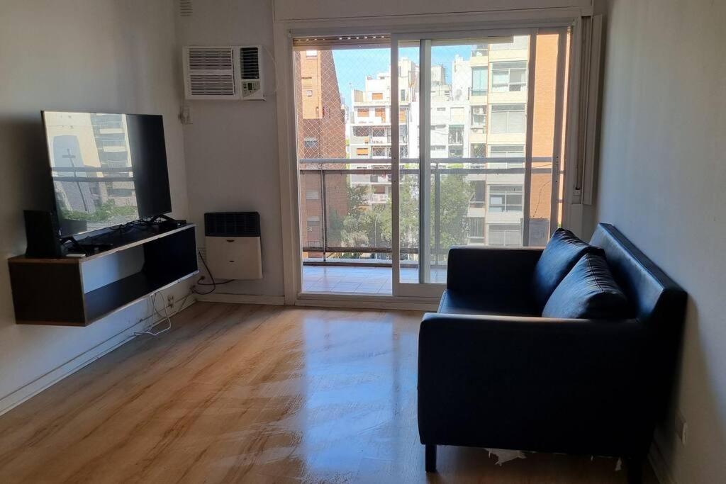 ein Wohnzimmer mit einem Sofa und einem großen Fenster in der Unterkunft Hermoso departamento 4 personas in Buenos Aires
