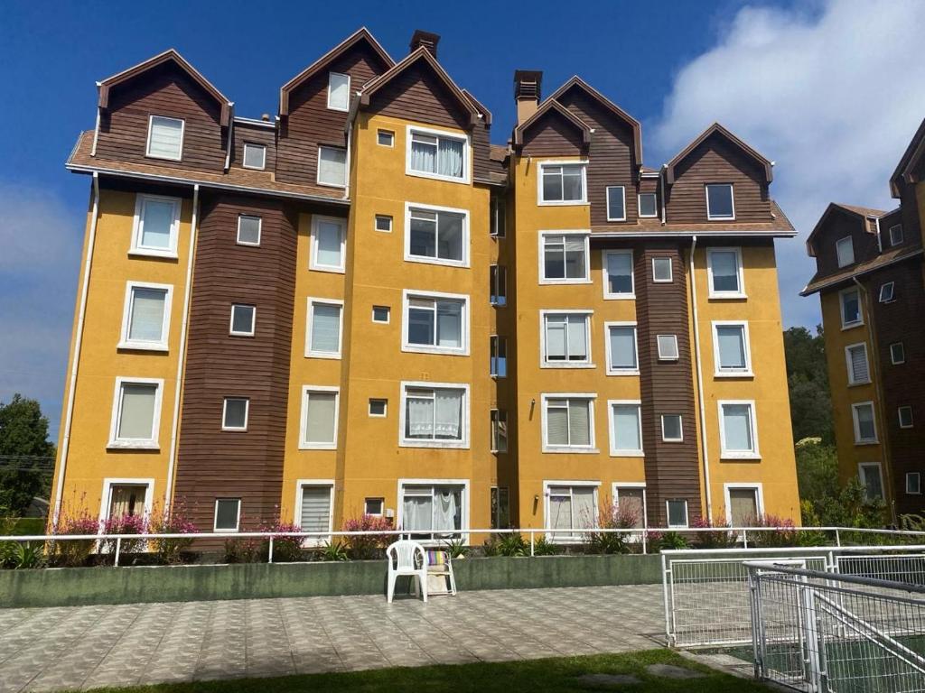a large yellow building with brown roof at Pucon departamento in Pucón