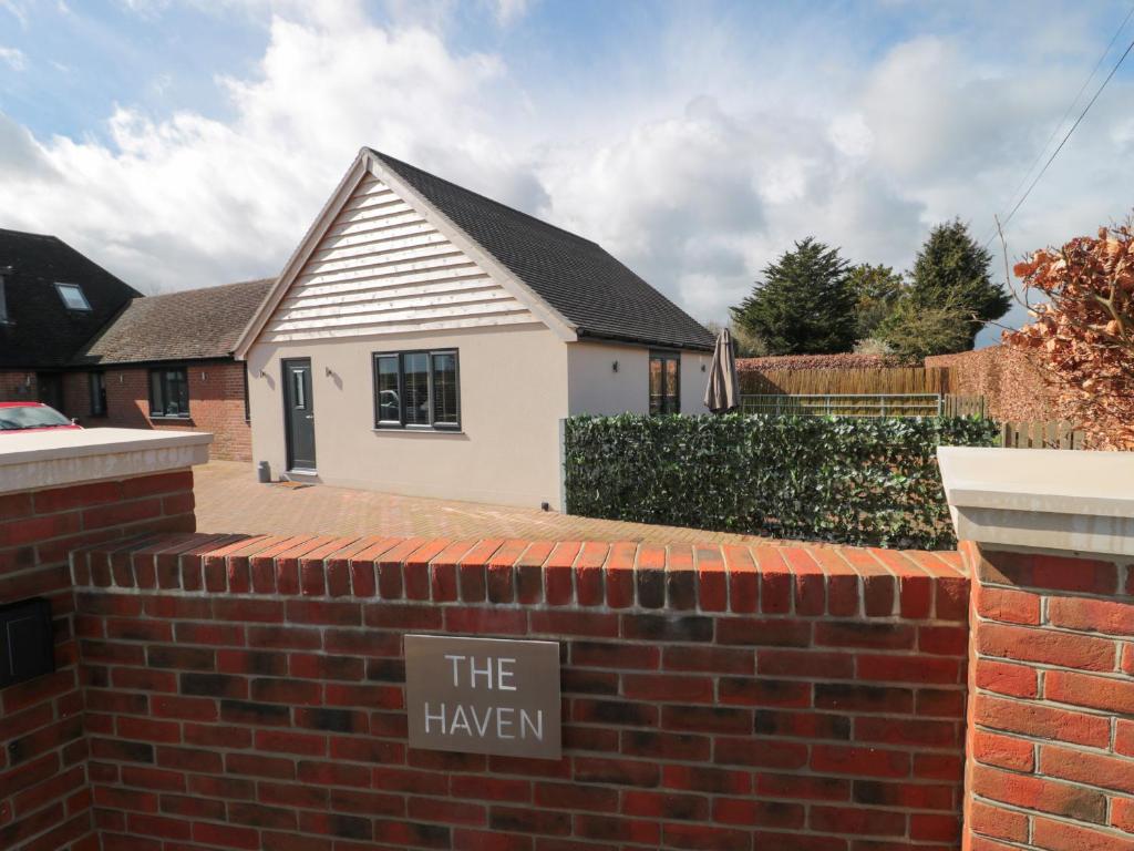 a brick wall with a sign that reads thehaven at Little Haven in Blandford Forum