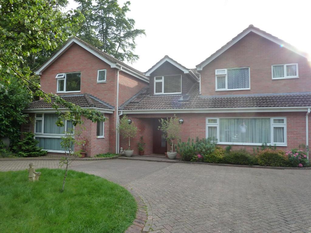 ein Backsteinhaus mit einer Einfahrt davor in der Unterkunft Cameron House in Landford