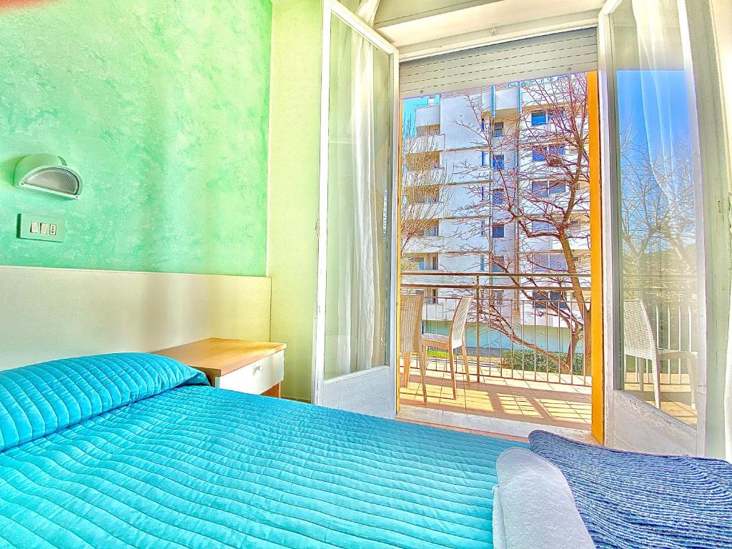 um quarto com uma cama azul e uma janela em Hotel Majorca Nuova Gestione Rimini 100 m dalla spiaggia em Rimini