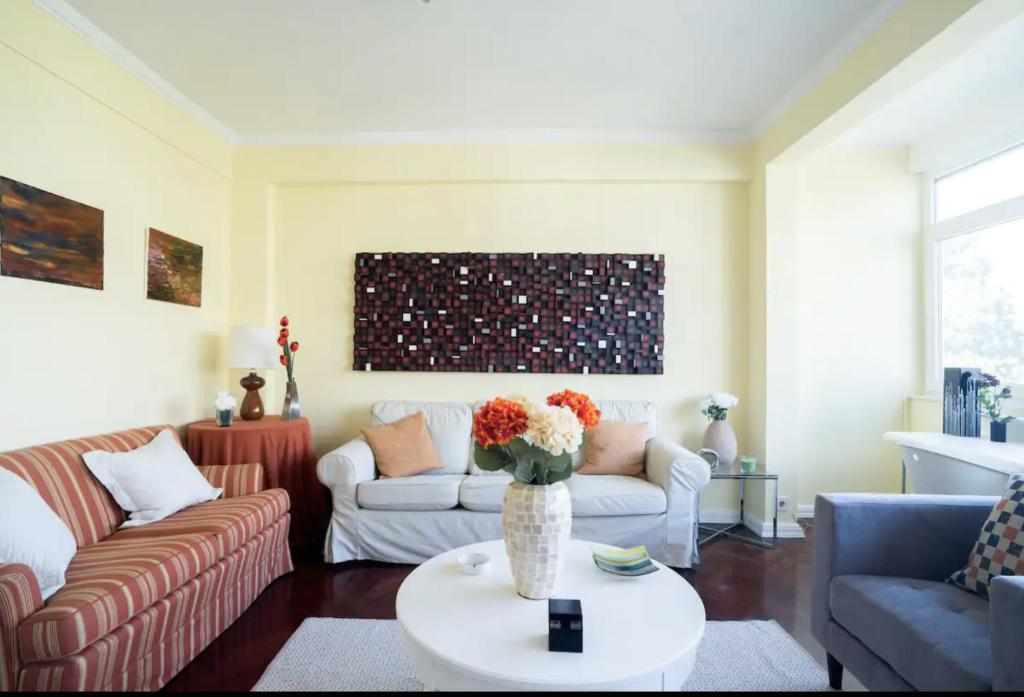 een woonkamer met een bank en een vaas met bloemen bij Spacious Apartment in Belém in Lissabon