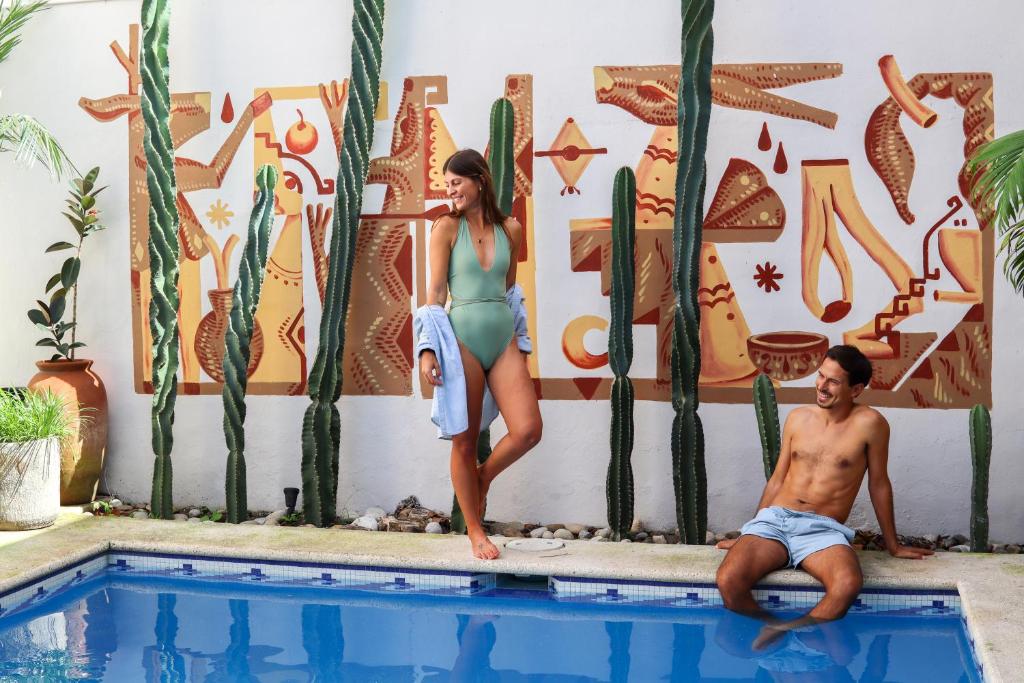 a man and a woman standing next to a swimming pool at Casa Encuentro De Joaquín Garcia in Mérida